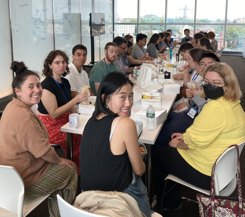 A group of people sit around a table, smiling for the photo