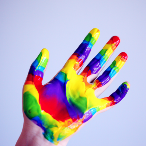 Hand covered in rainbow colored paint